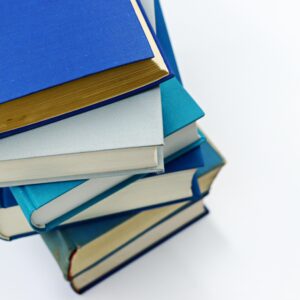 A vertical stack of books with blue covers on a white background symbolizes education and literature.